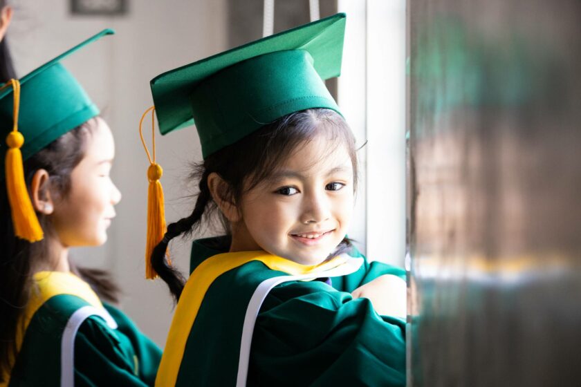 Little girl wearing graduation outfit.