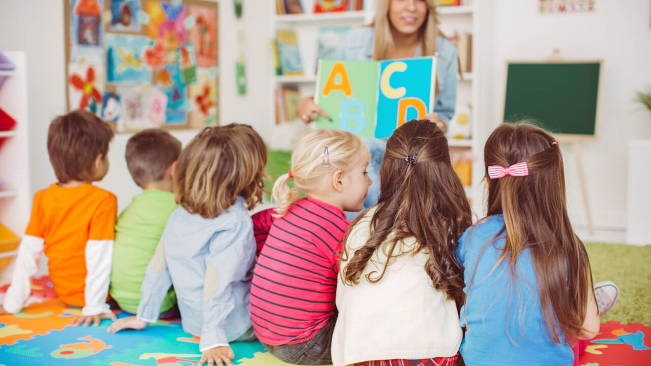 Teacher showing a book of letters to students.