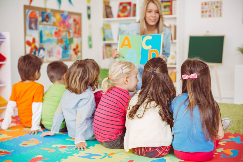 Teacher showing a book of letters to students.